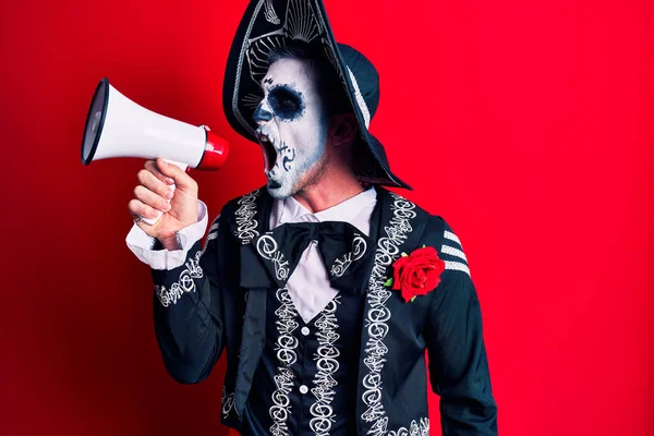 Scary man wearing day of the dead make up and costumbre from traditional ritual in Mexico shouting through megaphone