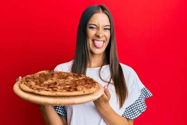 Jovem Hispânica Segurando Pizza Italiana Língua Furar Feliz Com Expressão — Fotografia de Stock