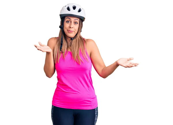 自転車のヘルメットを身に着けている若い美しい女性は 腕や手で混乱した表情を上げました 疑わしい概念 — ストック写真