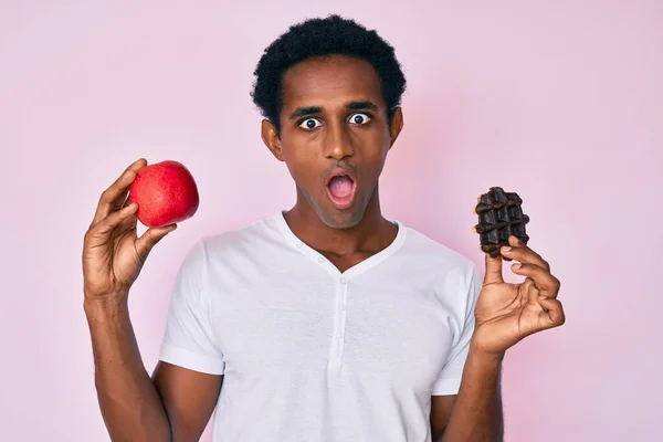 Hezký Africký Muž Drží Červené Jablko Čokoládové Vafle Strach Šokován — Stock fotografie