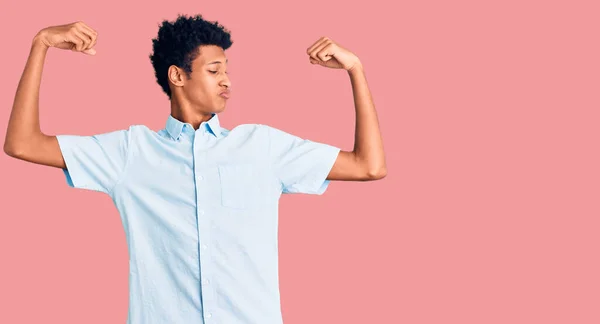 若いアフリカ系アメリカ人の男性は腕の筋肉を示すカジュアルな服を着て誇らしげに笑っている フィットネスのコンセプト — ストック写真