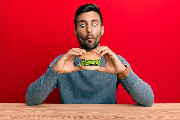 Hombre Hispano Guapo Comiendo Una Sabrosa Hamburguesa Clásica Haciendo Cara — Foto de Stock