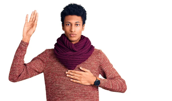 胸と手のひらに手で身に着けているカジュアルな冬のセーターとスカーフを身に着けている若いアフリカ系アメリカ人男性 忠誠の誓いを作る — ストック写真
