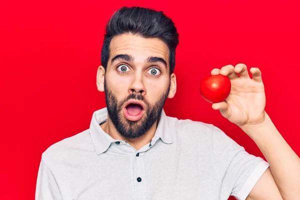 Ung Stilig Man Med Skägg Håller Tomat Rädd Och Förvånad — Stockfoto