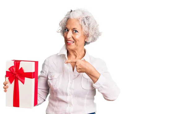 Senior Siwowłosy Kobieta Trzyma Prezent Uśmiechnięty Szczęśliwy Wskazując Ręką Palcem — Zdjęcie stockowe