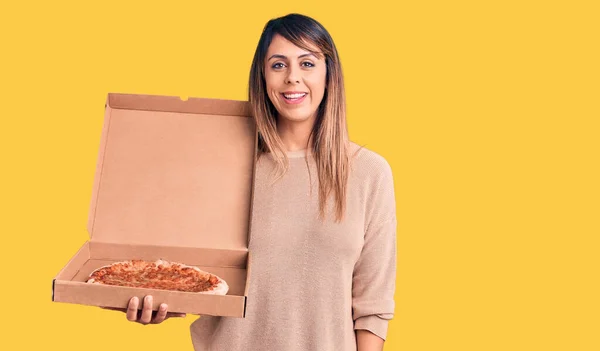若いです美しいです女性保持デリバリー段ボール箱でピザを探して正と幸せな立ちと笑顔で自信を持って笑顔を示す歯 — ストック写真