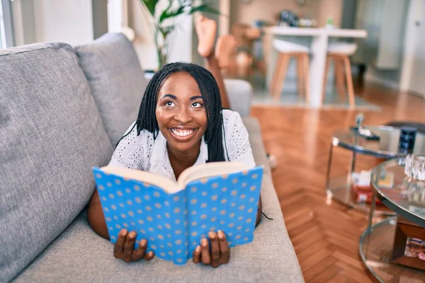 Mladý Africký Americký Žena Usměvavý Šťastný Polehávání Pohovce Čtení Knihy — Stock fotografie