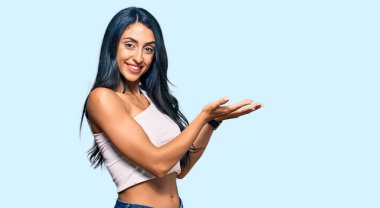 Güzel İspanyol kadın gündelik giysiler içinde avuçlarını açıp fotokopi alanını gösteren, gülümseyerek mutlu bir gülümseme sunan. 