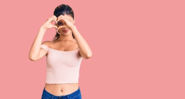 Genç ve güzel bir kadın günlük giysiler içinde kalp şeklinde eller ve parmaklar şeklinde tabelanın içinden bakıp gülümsüyor. 