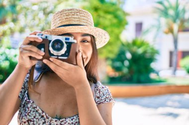 Şehrin caddesinde gezen eski model kamera kullanan genç Latin kadın..