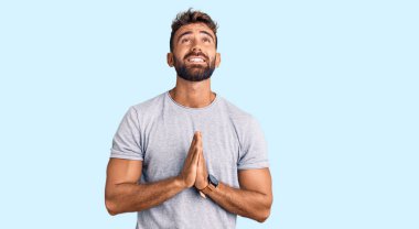 Gündelik giysiler giyen genç İspanyol adam elleri bağlı yalvarıyor ve dua ediyor. Yüzünde umut ifadesi var. Çok duygusal ve endişeli. Yalvarıyor. 