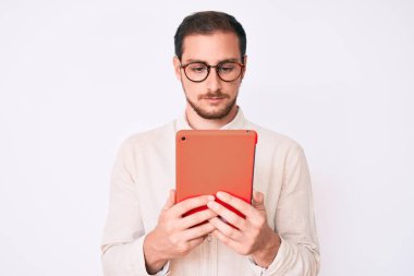 Genç yakışıklı adam dokunmatik bir cihaz kullanıyor. Düşünme tarzı ve ayık yüz ifadesi. Kendine güveniyor gibi görünüyor. 