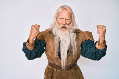 Gri saçlı, uzun sakallı, Viking kostümü giyen kızgın ve kızgın yaşlı bir adam öfkeyle bağırırken sinirli ve öfkeli yumruklar sallıyor. öfke ve agresif konsept. 