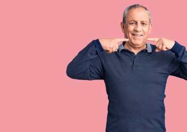 Son sınıf yakışıklısı sıradan polo giyen neşeli bir şekilde gülümseyen ve parmaklarıyla ve ağzıyla işaret eden. diş sağlığı kavramı. 