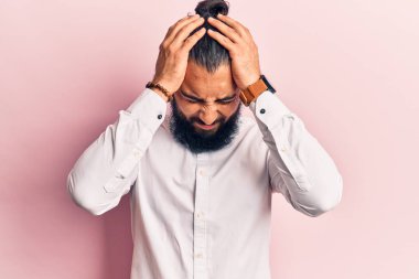 Genç Arap adam gündelik kıyafetler giyip baş ağrısı çekiyor. Acı ve migren yüzünden çaresiz ve stresli. Eller başının üstünde.. 