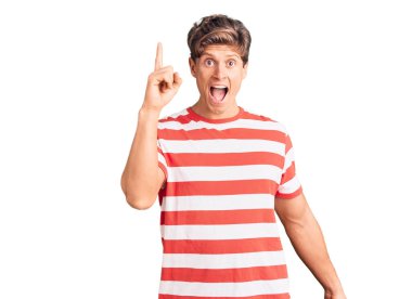 Gündelik giysiler giymiş genç yakışıklı bir adam başarılı bir fikri işaret ediyor. Heyecanlı ve mutlu. Bir numara.. 