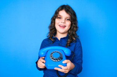 Uzun saçlı, eskimiş telefon tutan tatlı İspanyol çocuk. Gülmekten çatlıyor çünkü komik bir şaka.. 