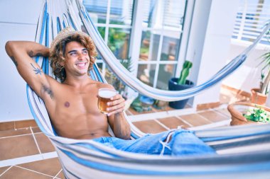 Genç İspanyol adam terasta hamakta uzanmış bira içerek rahatladı..