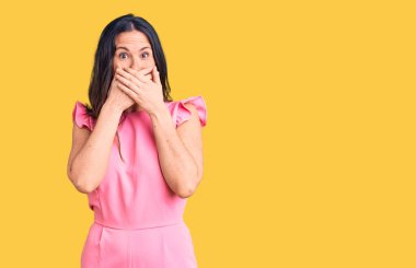 Genç, güzel, esmer, sıradan bir elbise giyen kadın yanlışlıkla elleriyle ağzını kapatırken şok oldu. gizli kavram. 