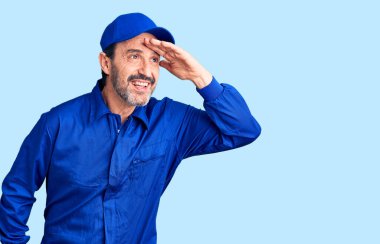 Orta yaşlı, yakışıklı, tamirci üniforması giyen çok mutlu ve gülümseyen bir adam. arama kavramı. 