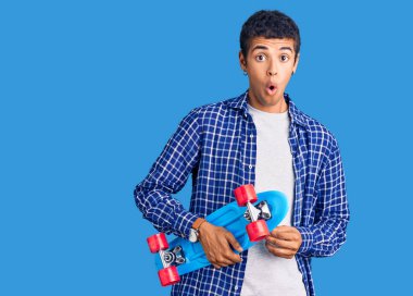 Genç Afrikalı Amerikalı kaykaycı, korkmuş ve ağzı açık bir şekilde şaşkınlık içinde, inançsız bir yüz ifadesi takınıyor. 