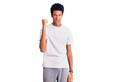 Genç, Afro-Amerikan bir adam, günlük kıyafetler giyiyor kızgın ve kızgın. Öfkeyle bağırırken yumruğunu kaldırıyor. öfke ve agresif konsept. 