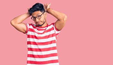 Yakışıklı Latin Amerikalı, günlük kıyafetler ve gözlük takan, tavşan kulağı yapan, avuç içi hareketleriyle kuşkucu ve şüpheci görünen bir genç. Paskalya tavşanı konsepti. 