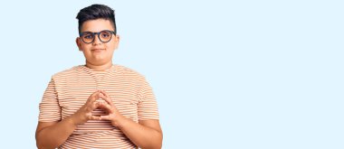 Günlük kıyafetler ve gözlük takan küçük çocuk ellerini birleştirip gülümseyerek gevşemiş ve neşeli olmasını diledi. Başarı ve iyimserlik 