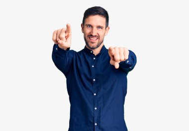 Seni ve kamerayı işaret eden, neşeli ve pozitif gülümseyen, gündelik gömlekler giyen genç yakışıklı adam. 