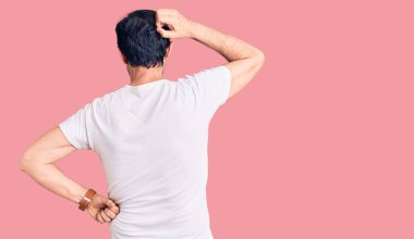 Orta yaşlı yakışıklı bir adam gündelik tişörtünü ters giyip elleri kafasında şüpheyi düşünüyor. 