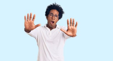 Afro saçlı, sıradan kıyafetler ve gözlüklü yakışıklı Afro-Amerikan adam. Avuçlarıyla jestleri durduruyor. Öfkeli ve hayal kırıklığına uğramış yüz ifadesi. 