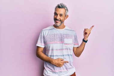 Orta yaşlı, gri saçlı, günlük kıyafetler giyen, gülümseyen, mutlu, eli ve parmağı yanda olan bir adam. 