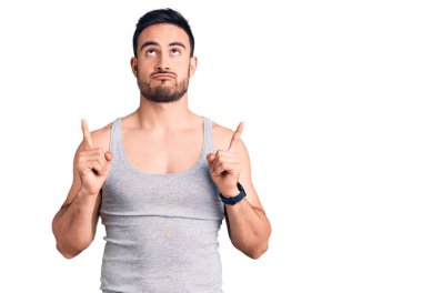 Mayolu ve kolsuz tişörtlü genç adam üzgün ve üzgün görünüyor, parmaklarıyla yönü gösteriyor, mutsuz ve depresif.. 