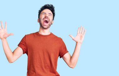 Gündelik kıyafetler giyen genç İspanyol adam deli gibi bağırıyor ve agresif bir ifade ve kollarla bağırıyor. hüsran kavramı. 