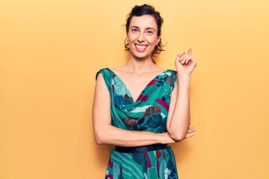 Genç ve güzel İspanyol kadın, gündelik elbiseler giyiyor. Gülümsüyor, mutlu bir şekilde elini ve parmağını yana uzatıyordu. 