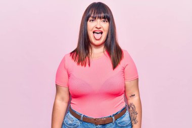 Genç ve cüsseli bir kadın günlük kıyafetler giyiyor. Dilini komik bir ifadeyle dışarı çıkarıyor. duygu kavramı. 