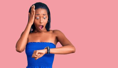 Genç Afro-Amerikalı kadın, günlük yaz kıyafetleri giyiyor. Saate bakıyor, endişeleniyor, geç kalmaktan korkuyor. 