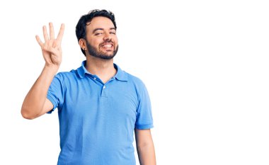İspanyol asıllı genç adam, gündelik giysiler giyip dört numarayı gösterip işaret ederken kendinden emin ve mutlu bir şekilde gülümsüyor.. 