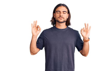 Gündelik kıyafetler giyen genç yakışıklı adam rahatla ve gözleri kapalı gülümse parmaklarıyla meditasyon hareketi yapıyor. yoga konsepti. 