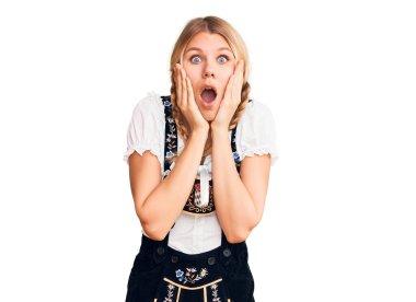 Oktoberfest elbisesi giyen genç, güzel sarışın kadın korkmuş ve şok olmuş, şaşırmış ve şaşırmış bir halde. 