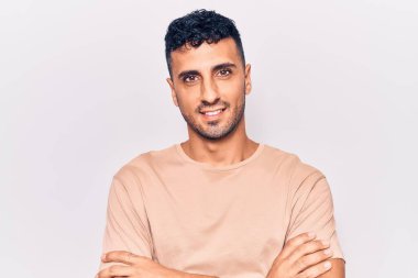 Gündelik kıyafetler giyen, kollarını kavuşturup kameraya gülümseyen genç İspanyol adam. pozitif kişi. 