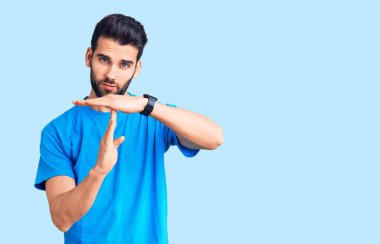 Sakallı, sıradan tişörtlü genç ve yakışıklı bir adam. Elleriyle jest yapıyor. Hayal kırıklığına uğramış ve ciddi bir yüz ifadesi var. 