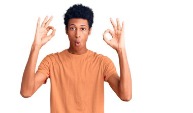 Gündelik giysiler giymiş genç Afro-Amerikan bir adam parmaklarıyla onay sembolü yaparken şaşırmış ve şok olmuş görünüyor. çılgın ifade 