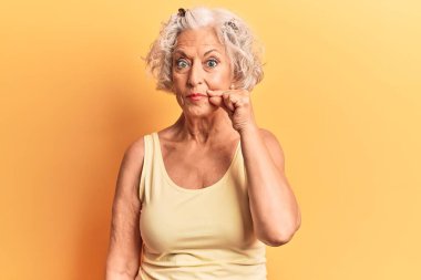 Son sınıf gri saçlı kadın günlük kıyafetler giyiyor ağzı ve dudakları parmaklarıyla fermuar gibi kapalı. gizli ve sessiz, tabu konuşması 