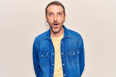 Gündelik giysiler giyen genç yakışıklı adam korkmuş ve ağzı açık kalmış, şaşırmış ve şaşırmış. 