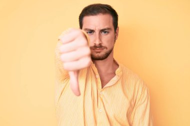 Gündelik kıyafetler giyen, mutsuz görünen, reddedilmiş ve olumsuz davranan genç yakışıklı bir adam. kötü ifade. 