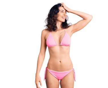 Bikini giyen, kendine güvenen, el hareketleriyle saçlarına dokunan çekici ve şık pozlar veren güzel İspanyol bir kadın. 