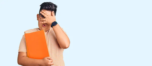 Niño Pequeño Sosteniendo Libro Con Gafas Mirando Shock Cubriendo Cara —  Fotos de Stock