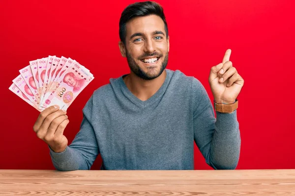 Hombre Hispano Guapo Sosteniendo Billetes Chinos Yuan Sonriendo Feliz Señalando —  Fotos de Stock