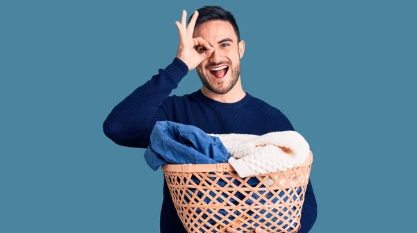 Jovem Homem Bonito Segurando Cesta Roupa Sorrindo Feliz Fazendo Sinal — Fotografia de Stock